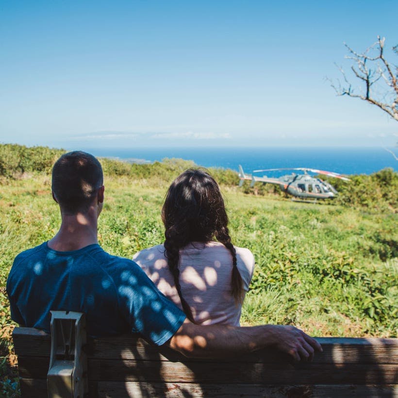 A couple sitting on a bench overlooking a beautiful vista 