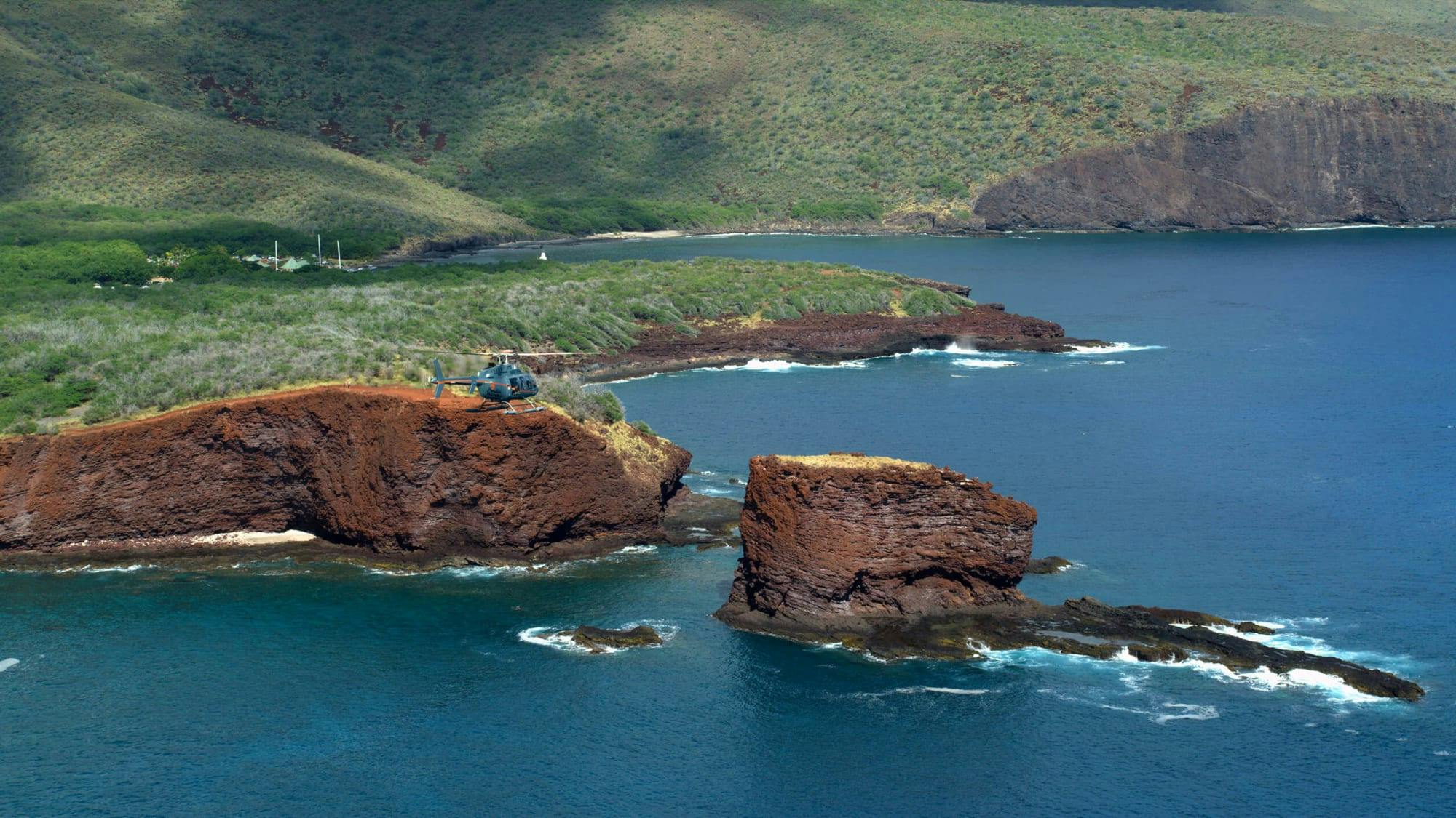 lanai coast with a helicopter flying over rock formations 