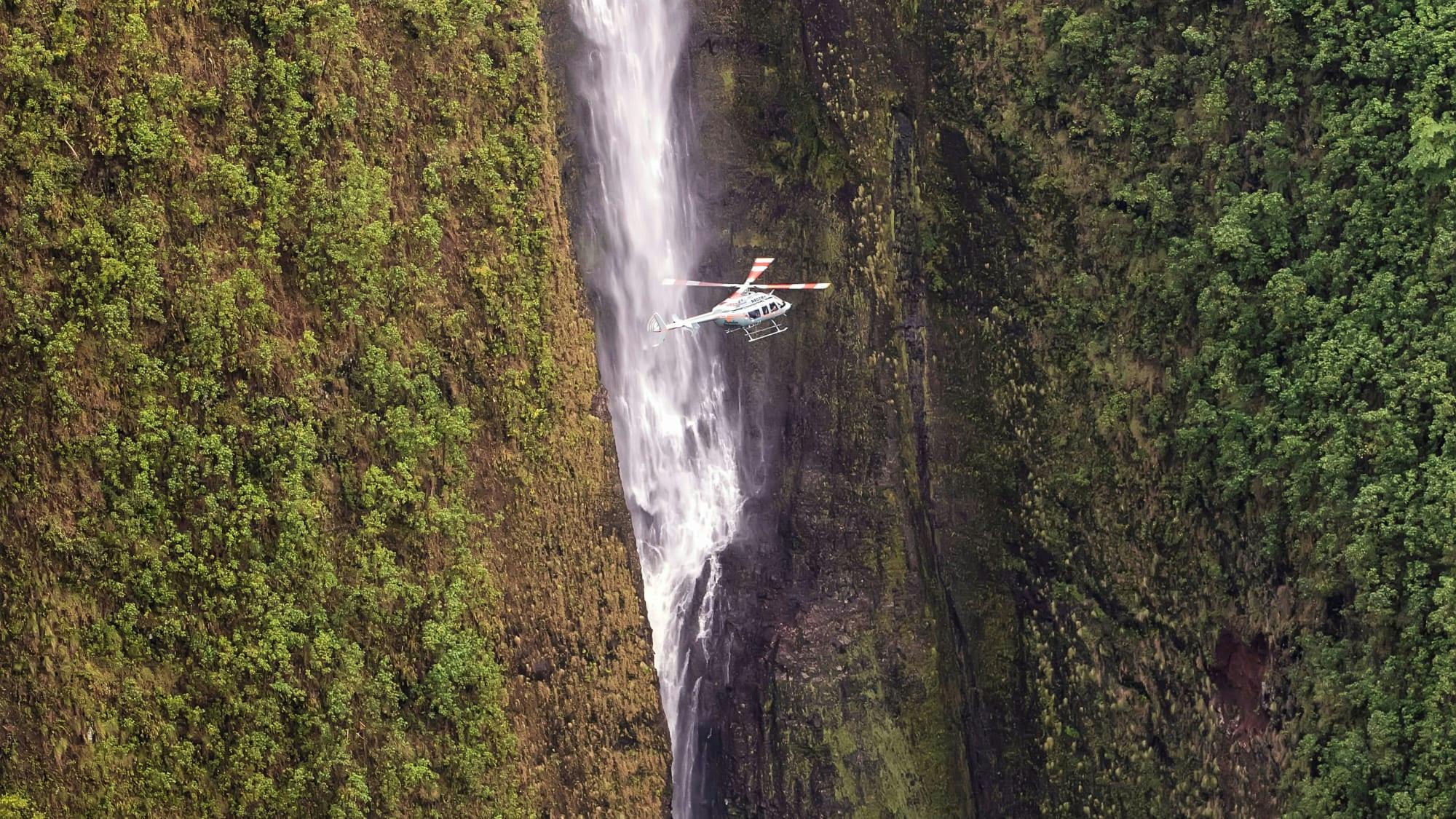 Helicopter flying next to a waterfall