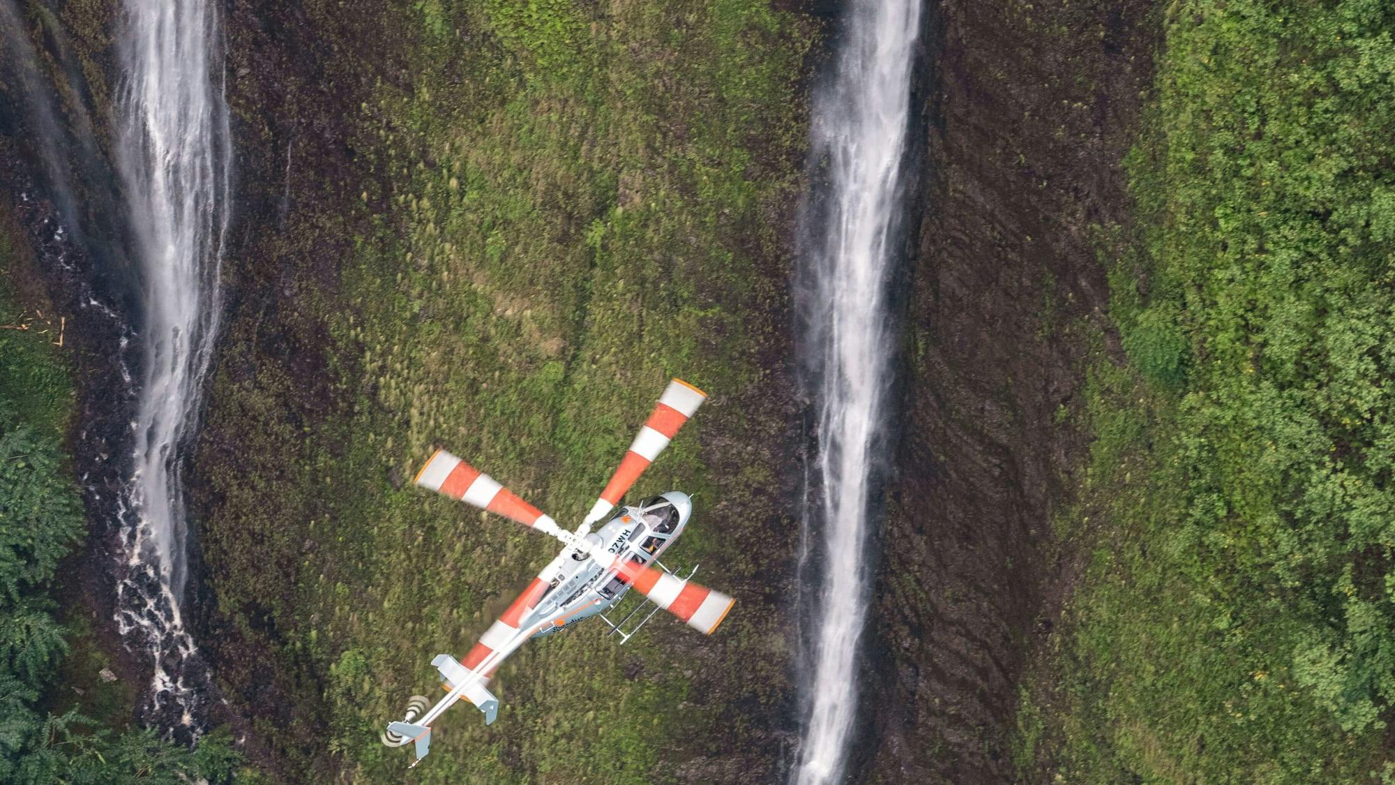 Helicopter flying next to waterfalls 