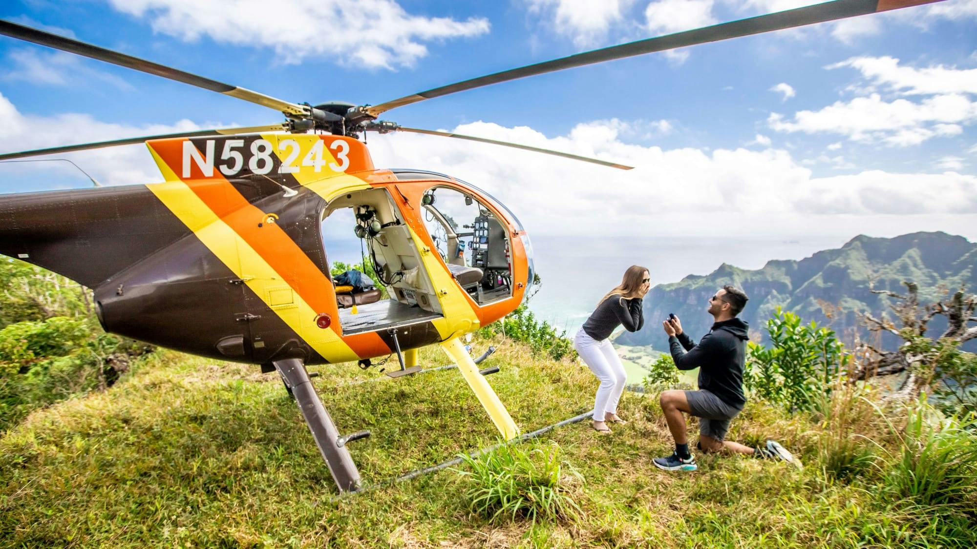 a man proposing to a woman next to the Magnum P.I. helicopter 