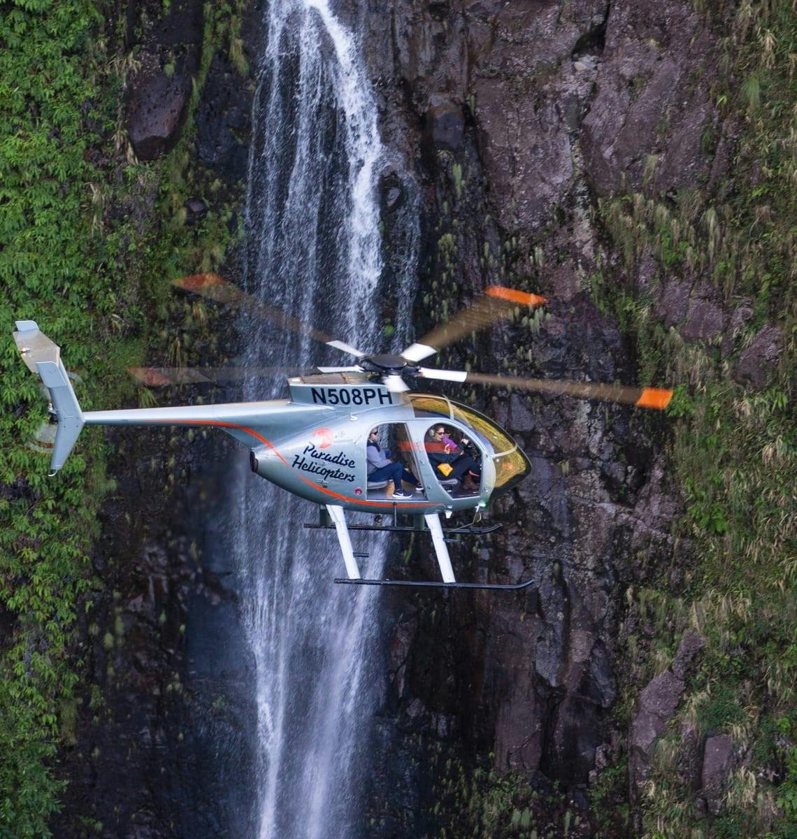Helicopter flying next to a waterfall 